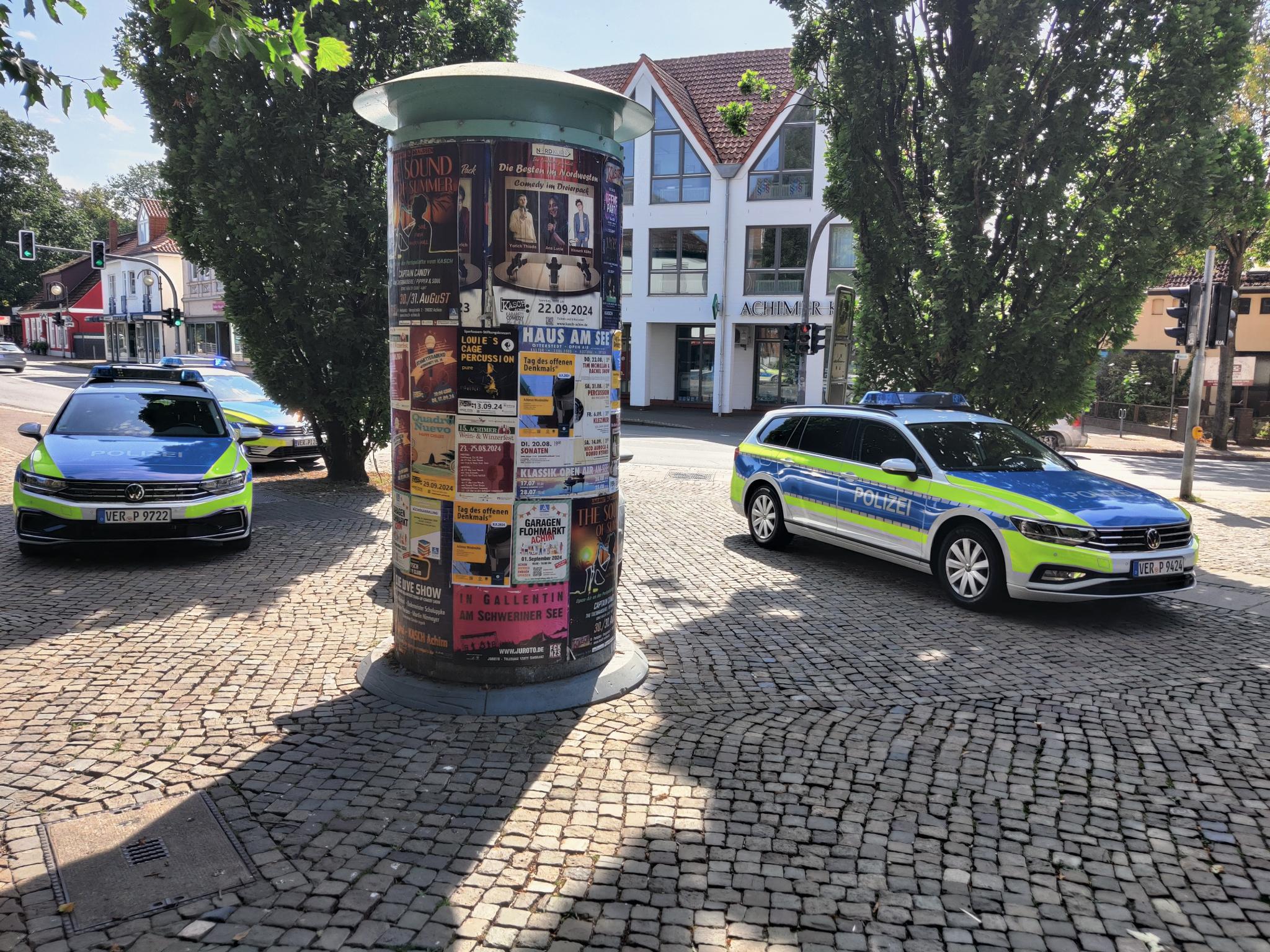 Polizeiautos neben Litfaßsäule